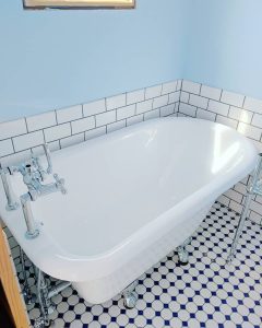 claw foot tub against tile floor and blue wall